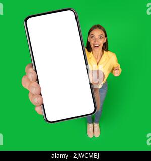 Quadratische Aufnahme Der Aufgeregten Dame Mit Großem Telefon, Grünem Hintergrund Stockfoto