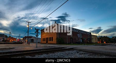 Troy, Alabama, USA - 3. September 2022: Das verlassene Backsteinlager der Henderson-Black Grocery Company (erbaut 1920) wurde während der Zeit von einer Straßenbeleuchtung beleuchtet Stockfoto