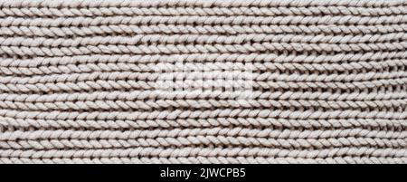 Stricken. Vertikale gestreifte beige Strickstruktur, Hintergrund mit Strickmuster. Draufsicht, Banner. Stockfoto