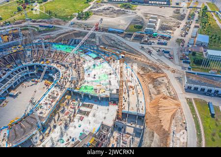 Bau auf einer riesigen Baustelle Kräne, Baustoffe. Das Konzept des Baus von großen Industrie- oder Sportanlagen Stockfoto