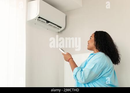 Afroamerikanische Frau, Die Die Klimaanlage Anmacht, Steht Zu Hause Stockfoto