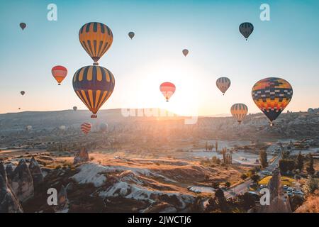 Kappadokien Sonnenaufgang Heißluftballons fliegen über Goreme Tal Landschaft mit Steinhöhlen. Menschen in bunten Heißluftballons genießen wunderbare Morgenstunden beobachten, Luftaufnahme. Tourismus, Reisen Urlaub Hintergrund Stockfoto