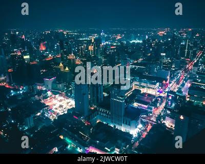 Nächtliches Stadtbild mit Wolkenkratzern, Straßen und elektrischen Lichtern. Städtische Skyline, Dämmerung, Architektur, beleuchtete Stadt. Blauer Tonungsfilter. Luftaufnahme Stockfoto