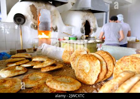 Taschkent Usbekistan - Bäcker, die im August 2022 in einer Bäckerei auf dem Markt des Chorsu Bazaar frisches rundes lokales Brot backen Stockfoto