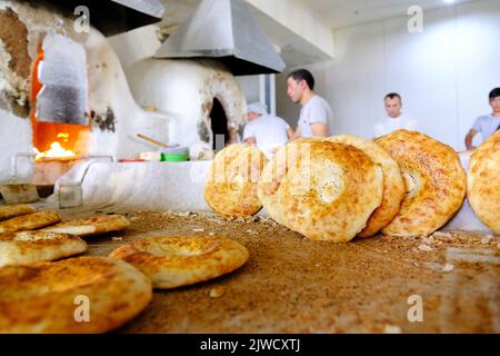 Taschkent Usbekistan - Bäcker, die im August 2022 in einer Bäckerei auf dem Markt des Chorsu Bazaar frisches rundes lokales Brot backen Stockfoto