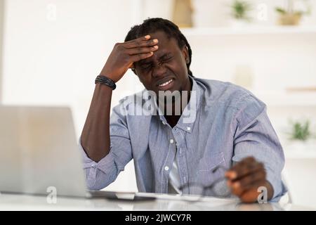 Verärgert Schwarz Männlich Leiden Kopfschmerzen Während Der Arbeit Mit Laptop Im Home Office Stockfoto