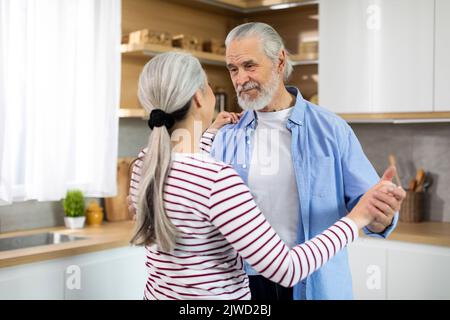 Gealterte Liebe. Porträt Von Romantischen Älteren Ehepartnern Tanzen In Küche Innenraum Stockfoto