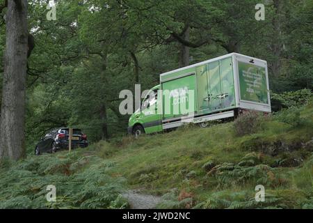 Ein Asda-Lieferwagen, der durch Wälder, Lake District National Park, Ullswater, Cumbria, England, Großbritannien fährt Stockfoto