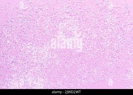 Winziges Konfetti aus silbernem Kristall auf violettem Hintergrund. Trendige, kreative Textur. Stockfoto