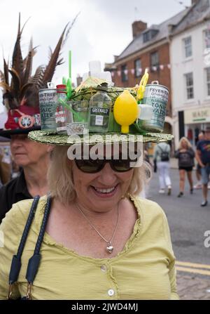 Lady in einem Gin und Tonic Hut genießt die Teilnahme am Bridport hat Festival Dorset 2022 Stockfoto