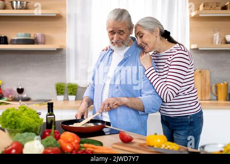 Portrait Of Loving Senior Pärchen Making Meal Together In Kitchen Stockfoto