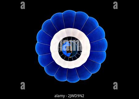 Blauer Heißluftballon, der auf schwarzem Hintergrund fliegt Stockfoto