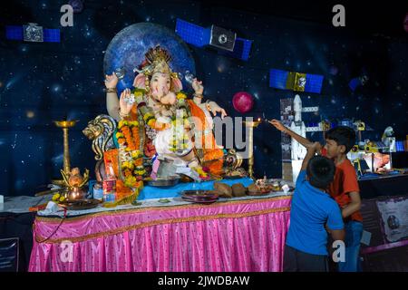 Zwei Jungen vor einem schönen Idol von Lord Ganesha in einem mandal in Mumbai für das verheißungsvolle indische Fest von Ganesh Chaturth Stockfoto