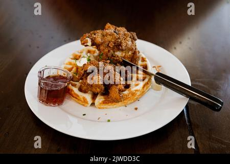 Ein Teller mit gebratenen Hähnchenstreifen und Waffeln und Ahornsirup Stockfoto