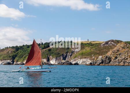 Ein Segelboot, das die Küste bei Dartmouth passiert. Stockfoto