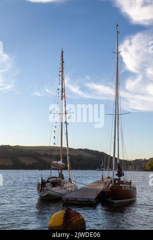 Abendlicht auf zwei klassischen Segelbooten aus Holz, die vor einem schwimmenden Ponton im River Dart, Dartmouth, festgemacht sind Stockfoto