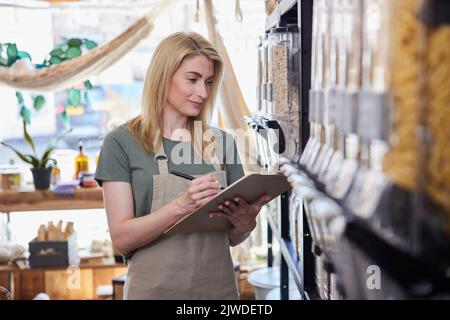 Besitzerin der Nachhaltigen Kunststoff Free Grocery Store Kontrolle Bestand in den Regalen Stockfoto