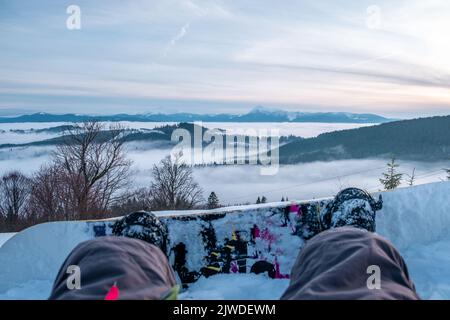 Snowboarder genießen den Blick auf den Sonnenuntergang über den Bergen Stockfoto