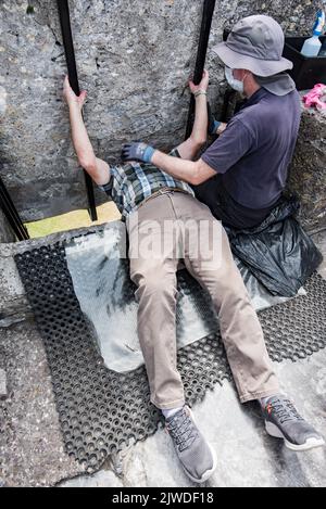 Kissing the Blarney Stone, ein Block aus kohlensäurehaltigem Kalkstein, der in die Zinnen von Blarney Castle and Gardens, Blarney, Co. Cork, Stockfoto