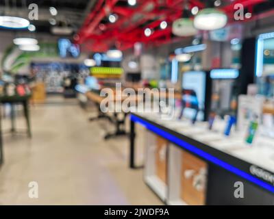 Schaufenster mit Smartphones im modernen Elektronikgeschäft. Kaufen Sie ein Mobiltelefon. Viele Smartphones im Regal des Technologiespeichers. Verschwommenes Bild als Stockfoto