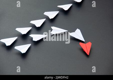 Rotes Papier Flugzeug Origami führenden weißen Flächen auf dunklem Hintergrund. Konzept der Führungsqualitäten. Stockfoto