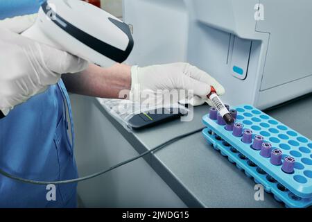 Labortechniker scannen den Barcode des Reagenzröhrchens mit Blut. Barcode-Etikett auf dem Reagenzglas zur Verfolgung von Blutproben Stockfoto
