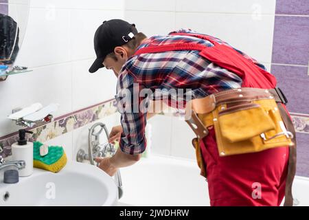 Kaukasische Klempner Tragen Installation Badezimmer Wasserversorgung In Neu Entwickelten Betonblöcken Gebäude. Thema Baustelle. Stockfoto