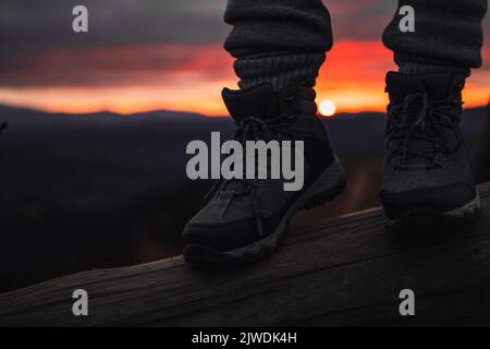 Person steht in Wanderschuhen im Freien vor dem wunderschönen Sonnenuntergang Stockfoto