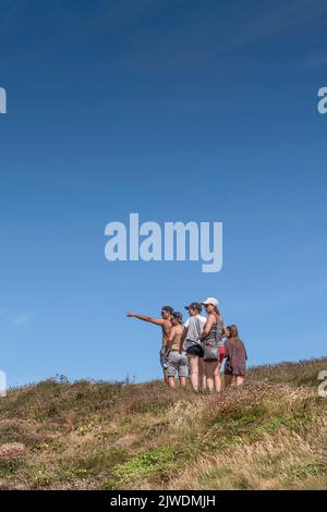 Urlauber, die einen Spaziergang entlang eines Küstenpfades in Newquay in Cornwall in Großbritannien genießen. Stockfoto