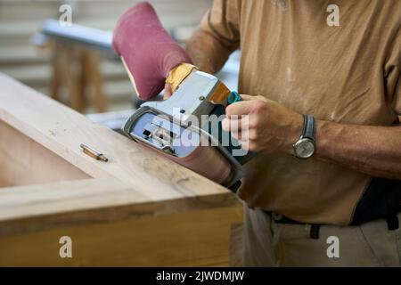 Antike Tischler arbeitet an Einem Schrank mit Einer Schleifmaschine. Russikon, Zürich Oberland, Schweiz Stockfoto