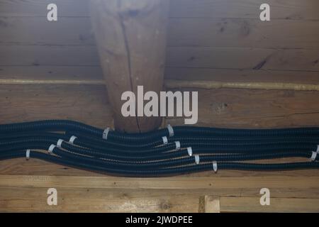 Elektrische Kabel mit Hilfe von durchdringenden hermetischen Klemmen durch die Luft in ein Holzhaus einführen. Stockfoto