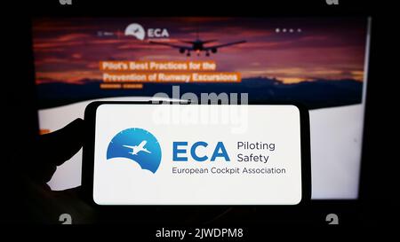 Person, die das Smartphone mit dem Logo der Organisation European Cockpit Association (ECA) auf dem Bildschirm vor der Website hält. Konzentrieren Sie sich auf die Telefonanzeige. Stockfoto