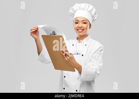 Lächelnde Köchin mit Klemmbrett und Stift Stockfoto