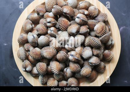 Draufsicht auf Herzmuscheln auf einem Teller auf schwarzem Hintergrund Stockfoto