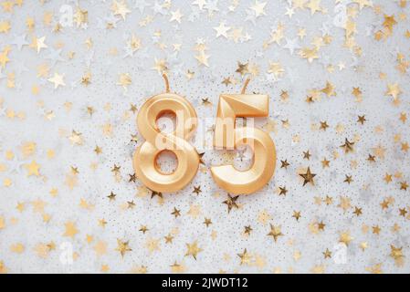 Nummer 85 fünfundachtzig goldene Feier Geburtstagskerze auf festlichen Hintergrund. Fünfundachtzig Jahre Geburtstag. Konzept der Feier Geburtstag, Jubiläum, wichtiges Datum, Feiertag Stockfoto