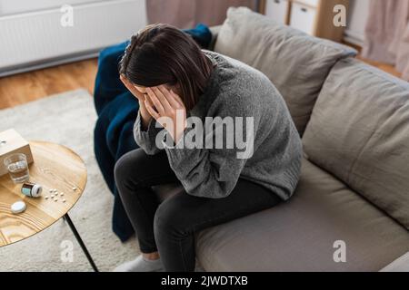 Gestresste Frau mit Medikamenten, die Kopfschmerzen hat Stockfoto