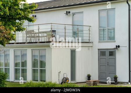 Blick auf Einfamilienhaus mit Terrasse und Balkon mit Fenstern mit Jalousien bedeckt Stockfoto