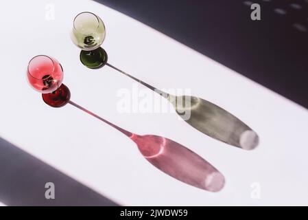 Zwei Weingläser auf weißem Hintergrund mit Licht und Schatten, Draufsicht Stockfoto