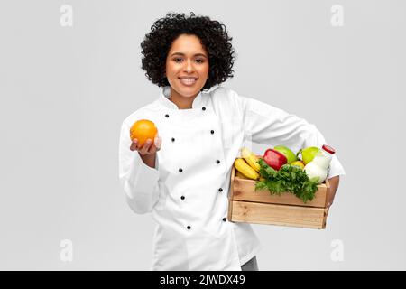 Glückliche lächelnde Köchin mit Essen in Holzkiste Stockfoto