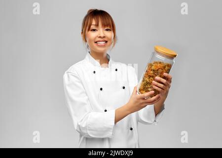 Lächelnde Köchin hält Glas mit Pasta Stockfoto