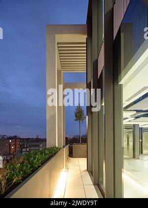 Blick auf die Außenfassade der oberen Etage in der Abenddämmerung. 50 Eastbourne Terrace, London, Großbritannien. Architekt: Sheppard Robson, 2021. Stockfoto