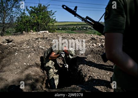 REGION SAPORISCHSCHSCHJA, UKRAINE - 02. SEPTEMBER 2022 - Ein Soldat gräbt den Boden an einer der Stellungen der ukrainischen Streitkräfte, wo sie die Verteidigungseinrichtungen durch die Installation von Metallbunkern, Saporischschschja, Südostukraine, verbessern. Stockfoto