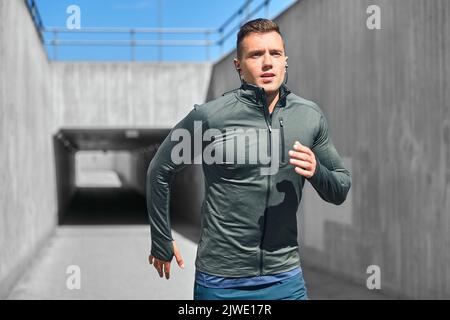 Junger Mann in Ohrhörern im Freien Stockfoto