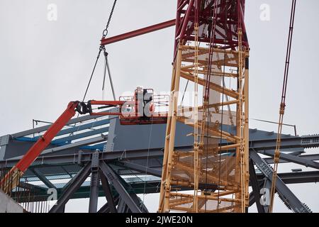 Zwei Bauherren in einem Cherry Picker Korb inspizieren die Baustelle der Anfield Road im September 2022 Stockfoto