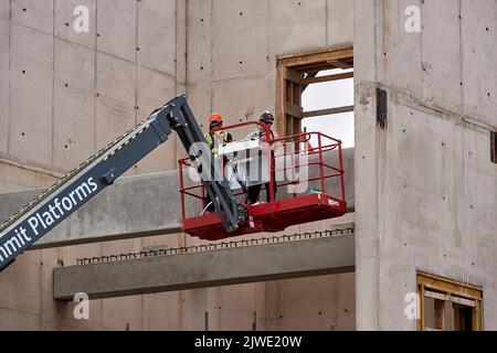 Zwei Bauherren in einem Cherry Picker Korb inspizieren die Baustelle der Anfield Road im September 2022 Stockfoto