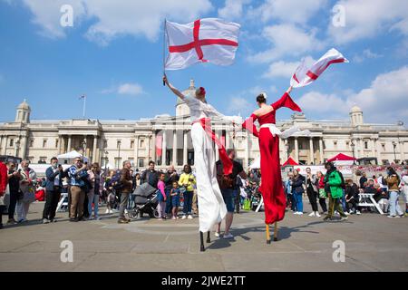 Die Menschen beobachten akrobatische Darbietungen, während sie sich zu den St. George’s Day Feiern auf dem Trafalgar Square im Zentrum von London versammeln. Stockfoto