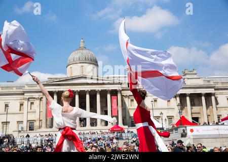 Die Menschen beobachten akrobatische Darbietungen, während sie sich zu den St. George’s Day Feiern auf dem Trafalgar Square im Zentrum von London versammeln. Stockfoto