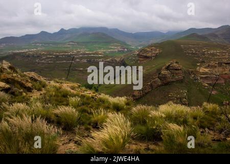 Die fernen blauen Berggipfel, umhüllt von dicken grauen Regenwolken, in den Drakensberg Mountains des Golden Gate Highlands National Park Stockfoto