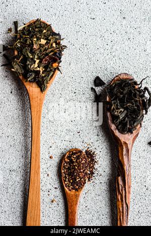 Blick von oben auf drei Holzlöffel mit verschiedenen Teesorten auf einem Tisch Stockfoto