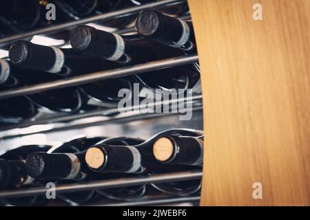 Weinflaschen horizontal in einem Weinregal mit Holz- und Metallstangen gelegt Stockfoto